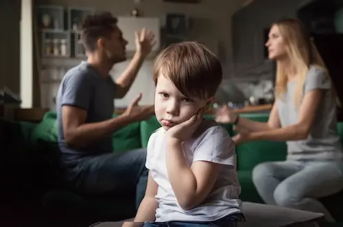 Two parents in house arguing with a young boy in foreground looking bewildered 