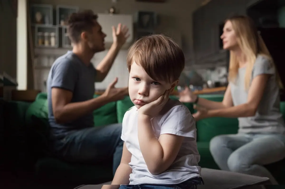Two parents in house arguing with a young boy in foreground looking bewildered 
