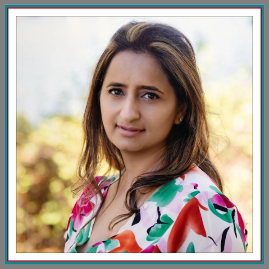 Professional outdoor headshot of Guneet Kohli, family lawyer at Pathway Legal, with highlighted auburn hair wearing a vibrant floral top against a warm soft outdoor background.