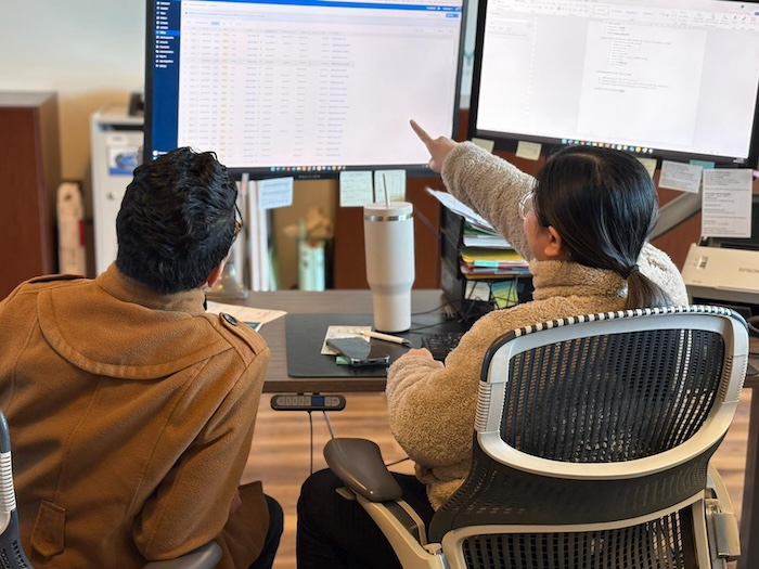 Two pathway legal staff in British Columbia with back to us, looking at a computer screen