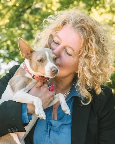 Val Hemminger affectionately holding and kissing her small dog, Inu.