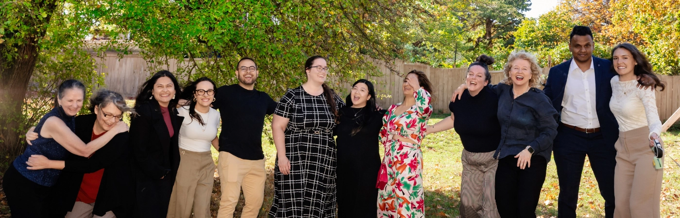 The Pathway Legal Pack, Fall 2026 A joyful candid group photo of the full Pathway Legal team laughing and hugging outdoors under autumn trees with golden fallen leaves, capturing the warmth, diversity, and genuine connection of the Pathway Legal pack in Fall 2026.