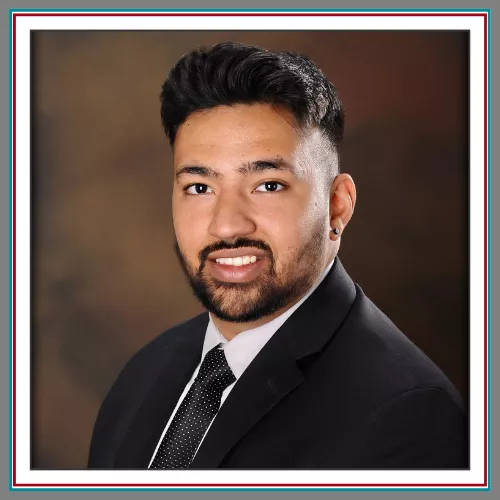 Professional headshot of Sartaj Malhi, Pathway Legal team member, in a dark suit and tie against a warm studio background.