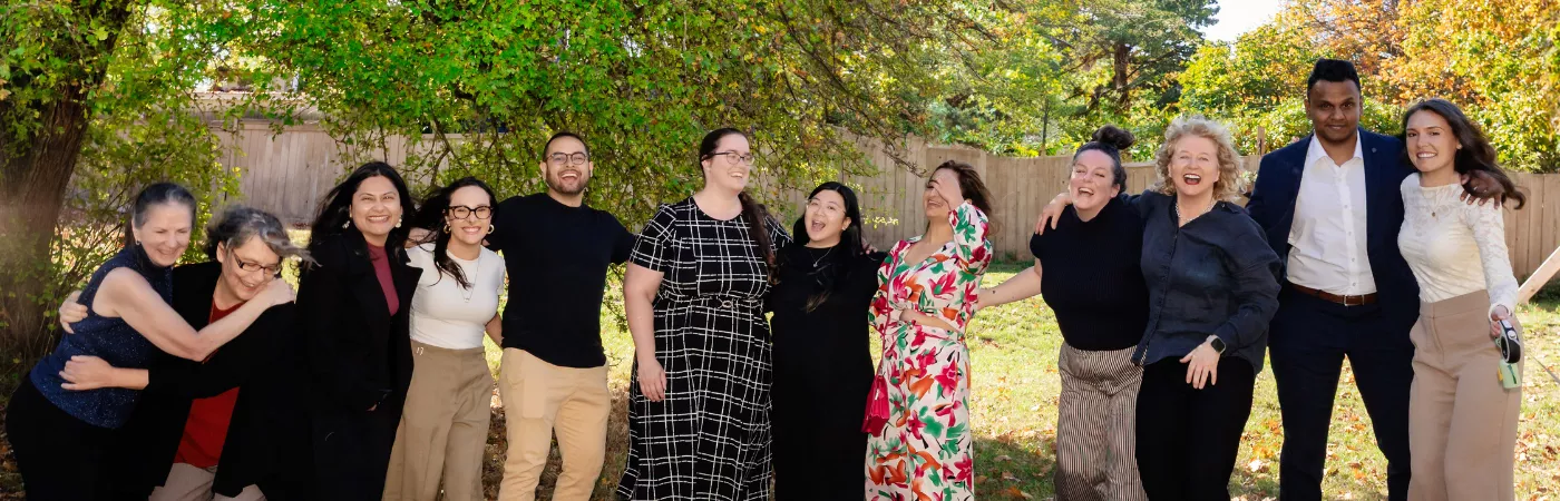 The Pathway Legal Pack, Fall 2026 A joyful candid group photo of the full Pathway Legal team laughing and hugging outdoors under autumn trees with golden fallen leaves, capturing the warmth, diversity, and genuine connection of the Pathway Legal pack in Fall 2026.